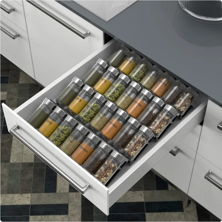 Spice jars arranged in four angled rows inside an open kitchen drawer