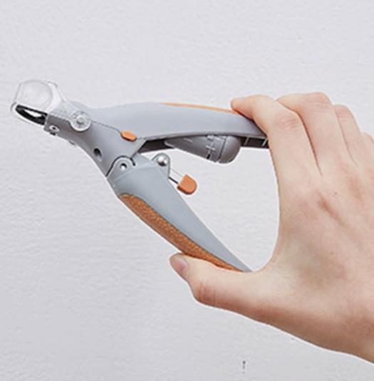 Gray manual pet nail clipper with LED light and clear magnifier held in a hand