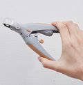 Gray manual pet nail clipper with LED light and clear magnifier held in a hand