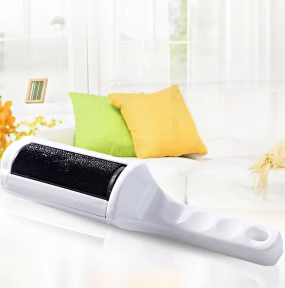 White reusable pet hair remover with black lint-collecting brush surface on a white sofa